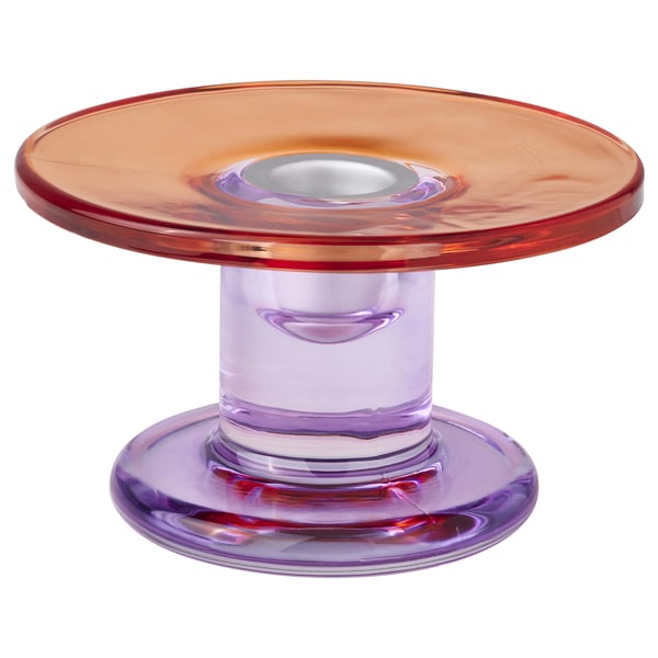 TJÄRLEK candlestick - orange-red glass, rounded shape, shiny finish, stands on purple glass base.