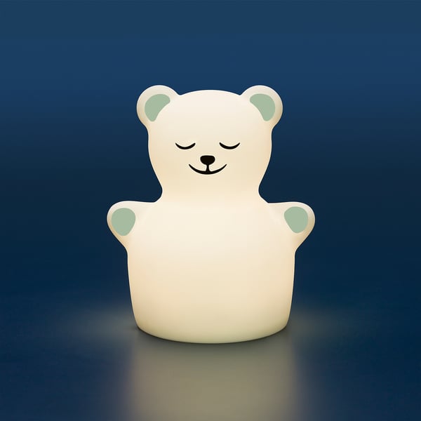 A white teddy bear night light with glowing green ears and closed eyes, providing a warm and gentle illumination.
