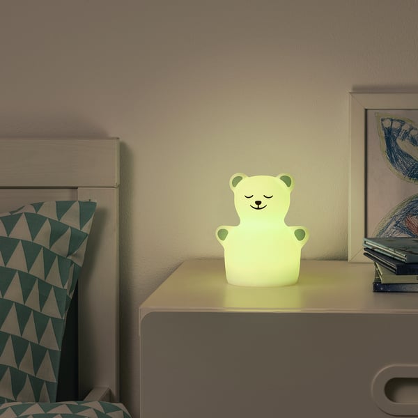 Cosy bedside table with TÖVÄDER bear nightlight and pillow.