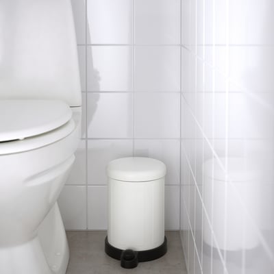 White bathroom rubbish can with a foot pedal for hands-free use, positioned next to a toilet.