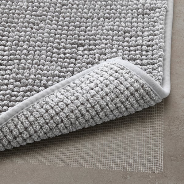 Close-up of a soft, textured grey bath mat with a non-slip mesh underside, ensuring safety and quick drying.