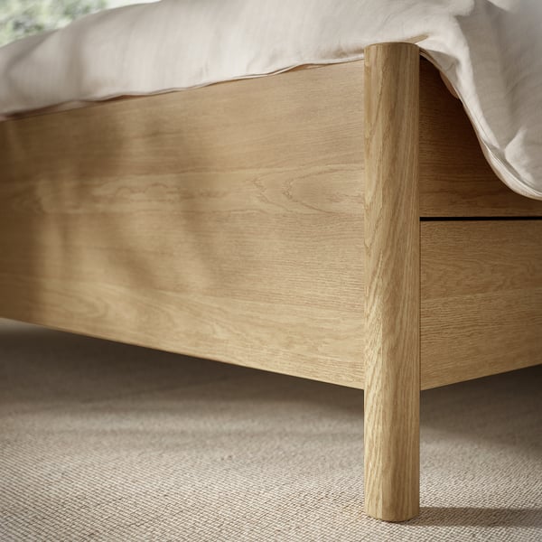 Minimalist wooden bed with light finish and soft-close drawer, showcasing quality craftsmanship.