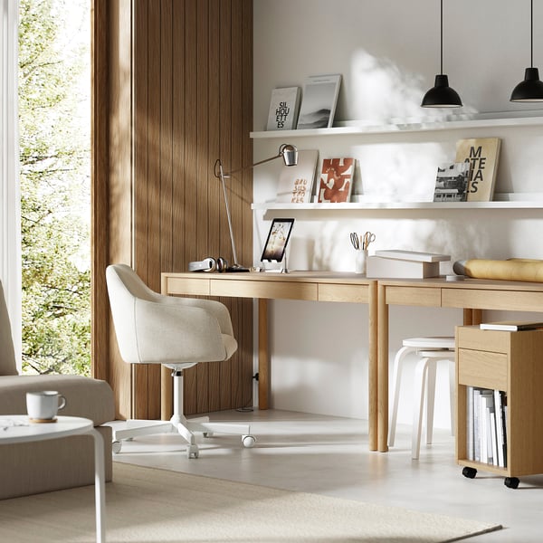 Modern home office with light wooden desk, white chair, and shelves. Oak veneer, clean design, and stylish accessories.