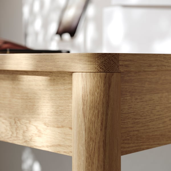 Close-up of TONSTAD desk corner, showcasing smooth oak veneer finish and robust craftsmanship.
