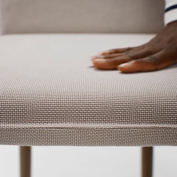 A beige upholstered couch with distinctive weave pattern, bare feet resting comfortably, highlighting its soft texture and quality.