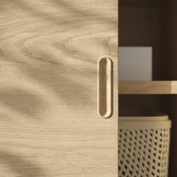 Light wooden cabinet door with sleek, modern handle. Brushed veneer finish gives elegant, unique texture.