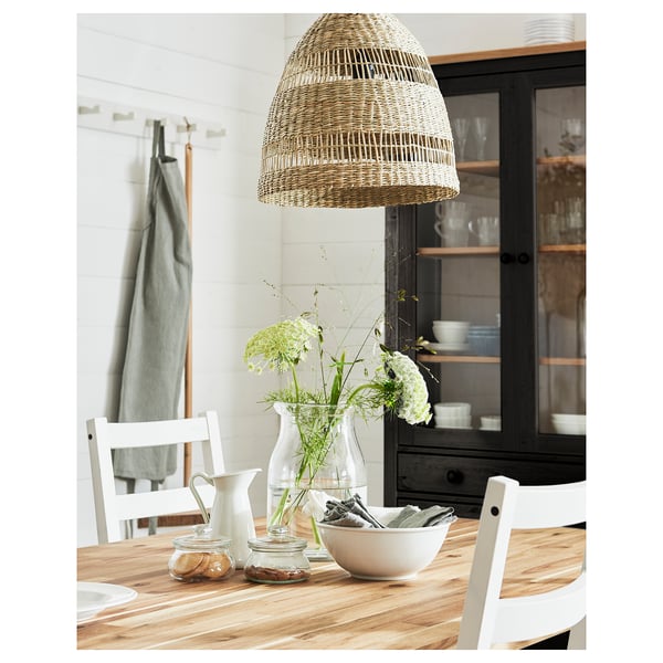 Cosy dining area with TORARED wicker pendant light, white chairs, wooden table, and fresh flowers.