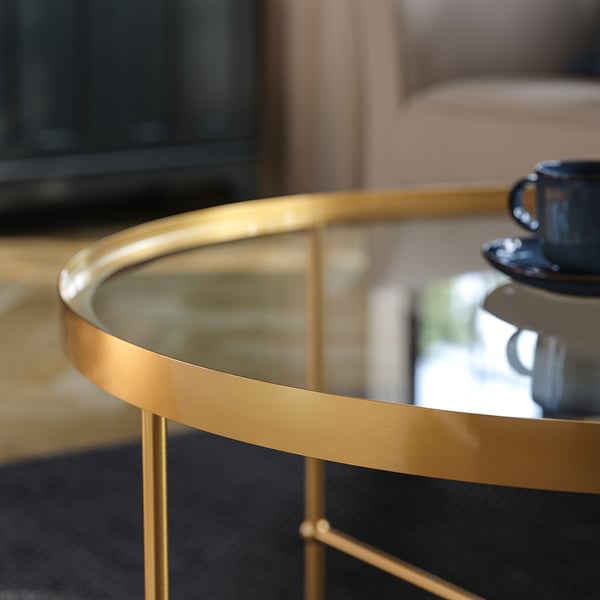 Elegant coffee table with gold metal frame and clear glass top, showing high-quality craftsmanship and refined design.