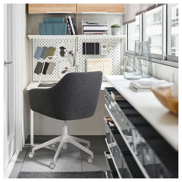 Modern home office with TOSSBERG grey swivel chair, white desk, pegboard storage, and large window.