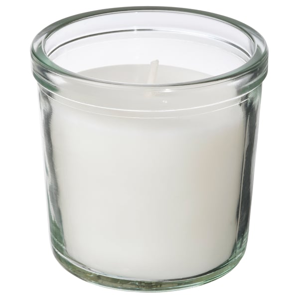 A TRÅDCYPRESS scented candle. Its white, in a clear glass jar, cylindrical with a simple design. The candle is mostly made of plant-based wax.