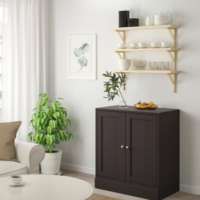 Modern living space with TRANHULT shelf, white dishes, fruit, plant, art.