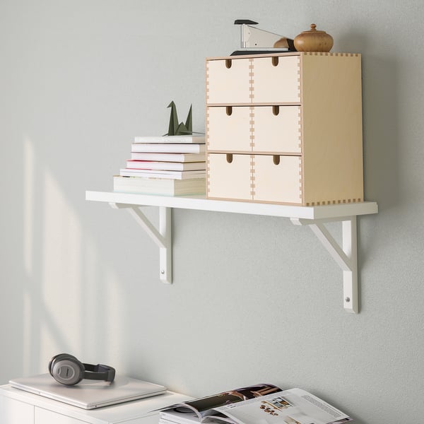 A wall-mounted shelf with wooden drawers and brackets. It stores books and holds various items.