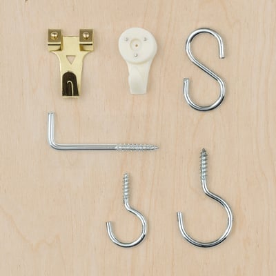 TRIXIG hardware set: gold and silver hooks, nails, and plastic box on wood.