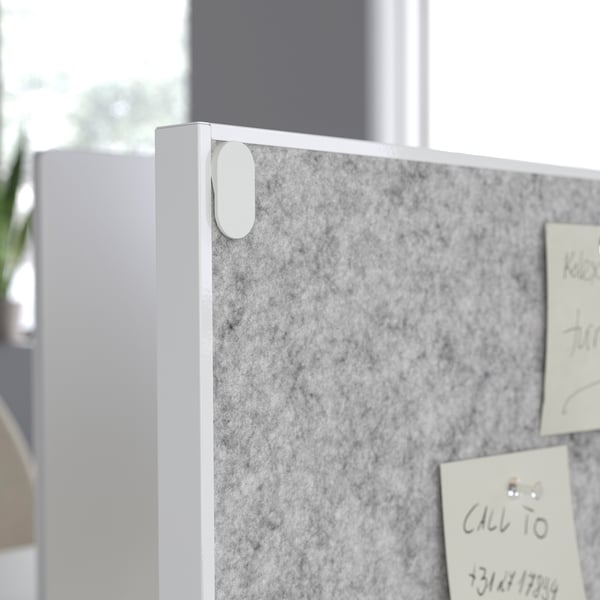 Grey double-sided board: one side for notes, one side for pinning reminders. Mounted on a white frame, it divides the workspace.