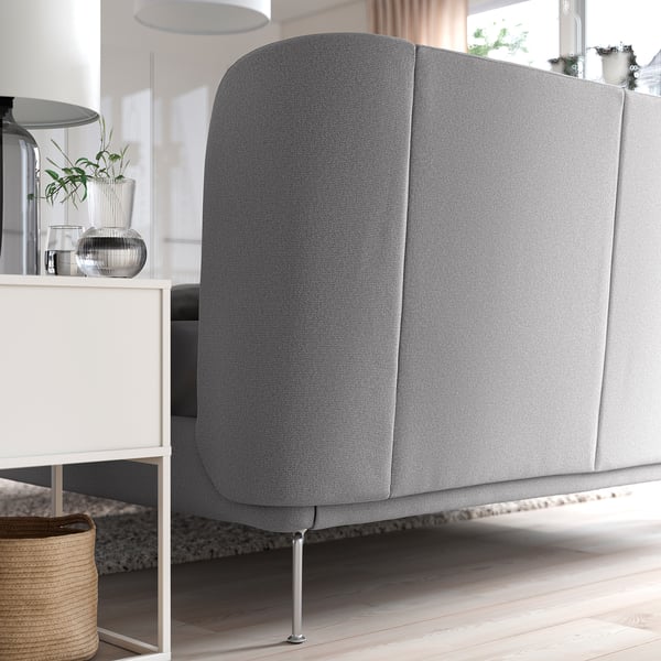 Large grey upholstered bed with curved headboard and metal legs stands in modern room.