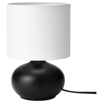 Modern desk lamp, TVÄRFOT. Black, oval stoneware base. White cylindrical shade. Simple, stylish design.