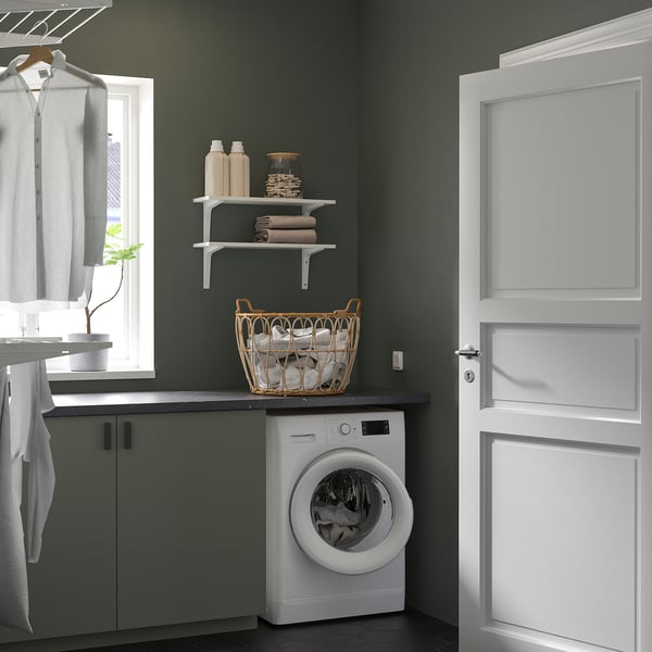 Small, white UDDARP combo washer/dryer fits neatly under green shelves, efficient for laundry in compact spaces.