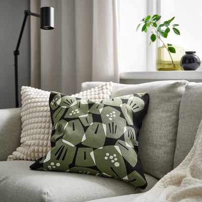 Cozy couch with leaf-patterned cushions, white pillow, black lamp, and plant.
