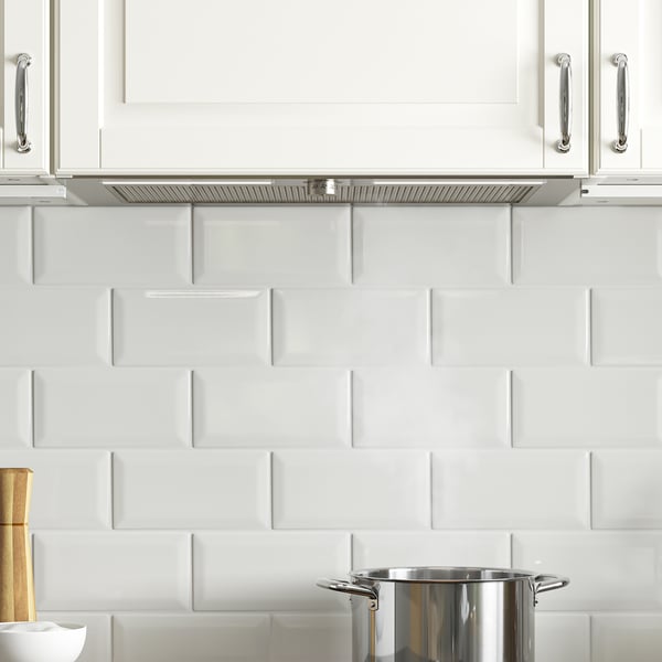 Modern kitchen with white cabinets, silver handles, and stainless cooktop. Hidden range hood with led lighting and grease philtre.