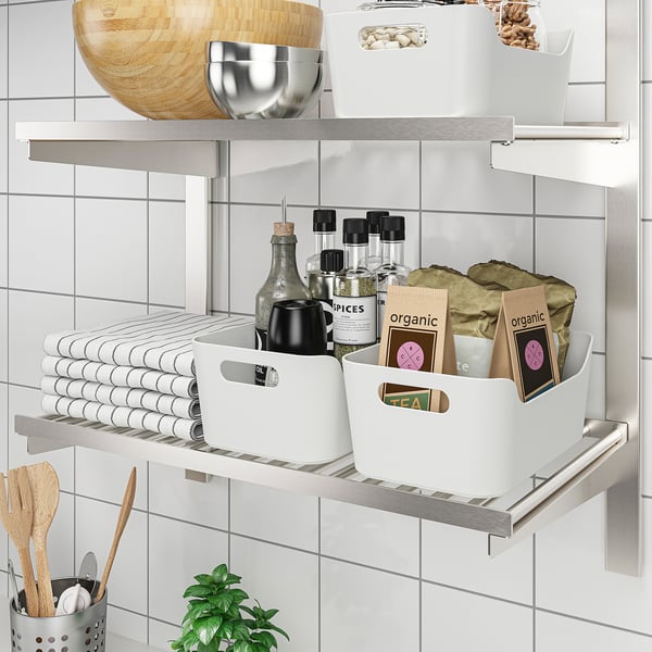 Organised kitchen shelves with storage bins, holding towels, spices, and organic items.