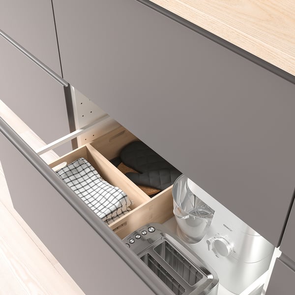 Open drawer, showing kitchen storage with boxes for towels, black fabric, blender, and toaster.