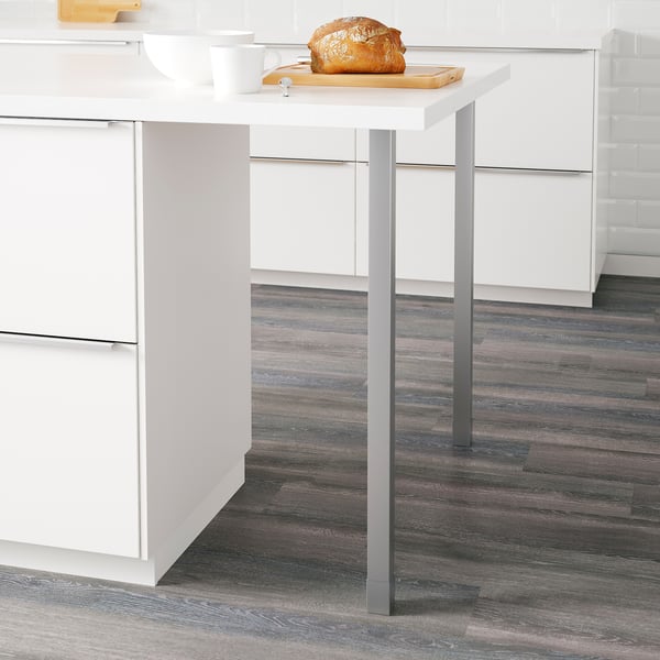 Small kitchen stand with adjustable metal legs supporting a wooden tabletop with a loaf of bread on it.