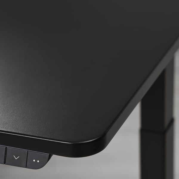 Modern gaming desk with sleek, matte black surface and adjustable height mechanism.