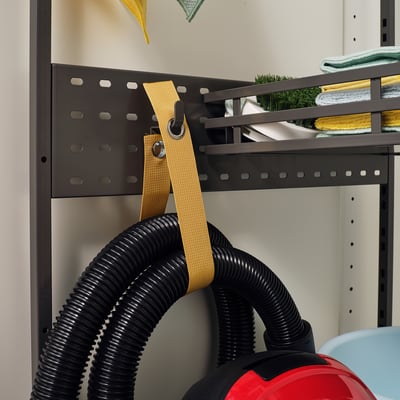 Vacuum hose stored on yellow strap on wall mount.
