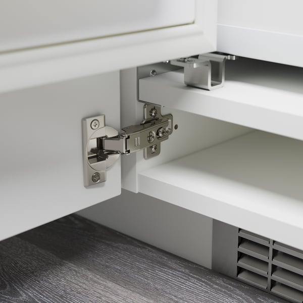 Metal hinge attached to white cabinet, adjustable in height, depth, and width.
