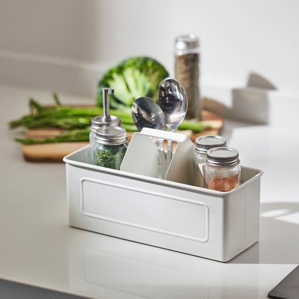 White kitchen organiser holds jars, utensils, and greens, keeping counter tidy and accessible.