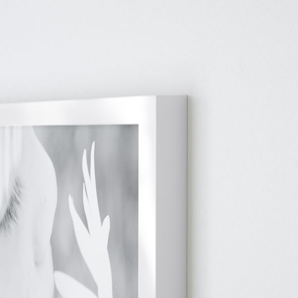 Corner of a white VÄXBO photo frame. Shows clean, crisp edges and sleek design. Set against a plain white wall, highlighting its minimalist style.
