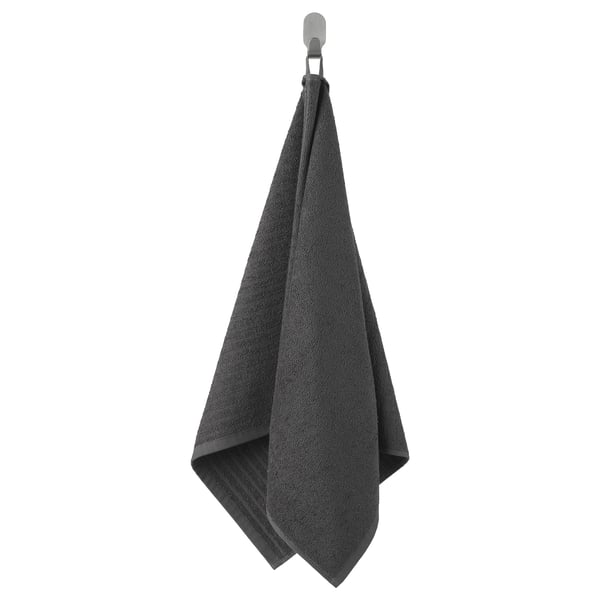 Dark grey VÅGSJÖN towel, hanging neatly on a hook, made of 100% cotton, rectangular shape.