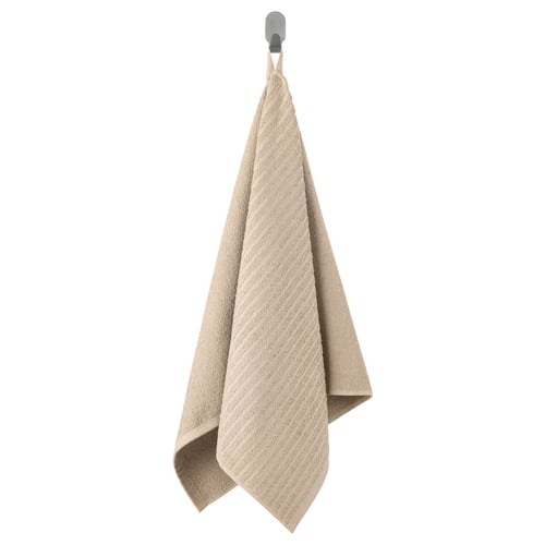 VÅGSJÖN beige towel hangs on grey hook. Soft, textured, rectangular, cotton.