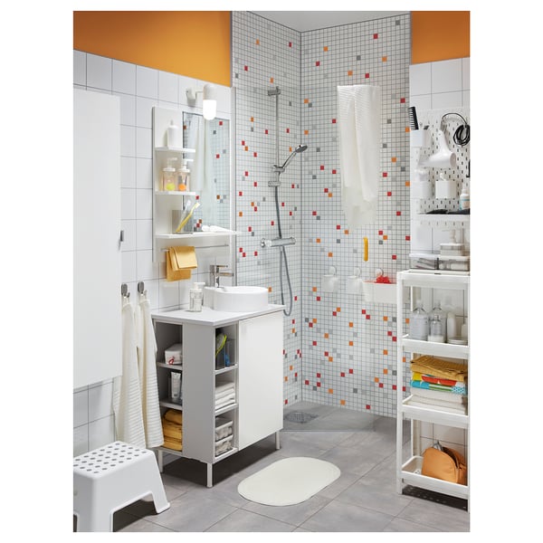 Well-organized bathroom with a white sink vanity, VALLAMOSSE shower with full spray, colourful mosaic tiles, and various storage solutions.