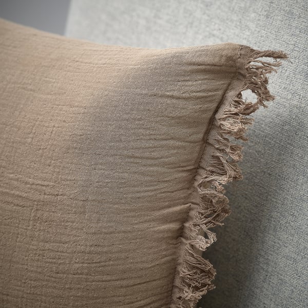 Soft, beige cushion cover with fringed edges and a slightly crinkled texture, showcasing high-quality craftsmanship.