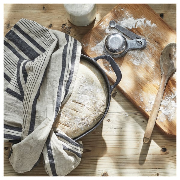 VARDAGEN cast iron pan in black, shown on wooden table with utensils.