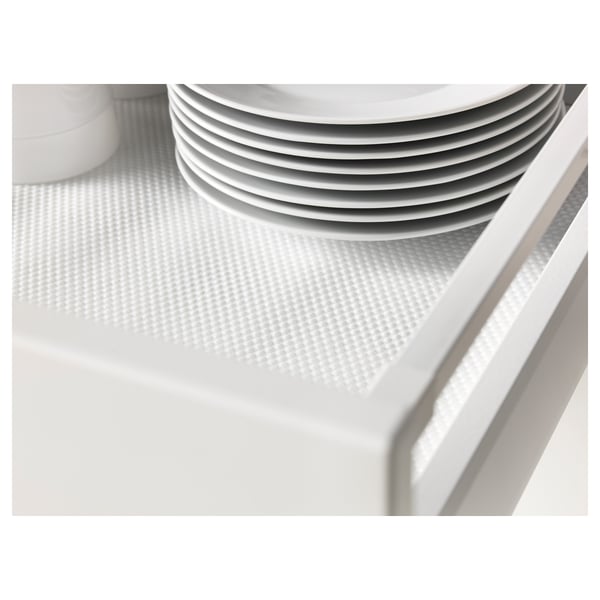 Stack of white plates neatly arranged on a patterned, non-slip drawer mat.