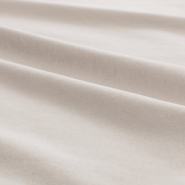Close-up of soft, light-colored fabric, likely cotton jersey, showing smooth texture and subtle sheen.