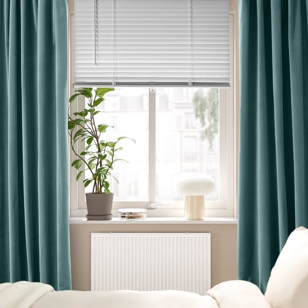 Modern window with VECKLARFLY blinds, turquoise curtains, and plant.