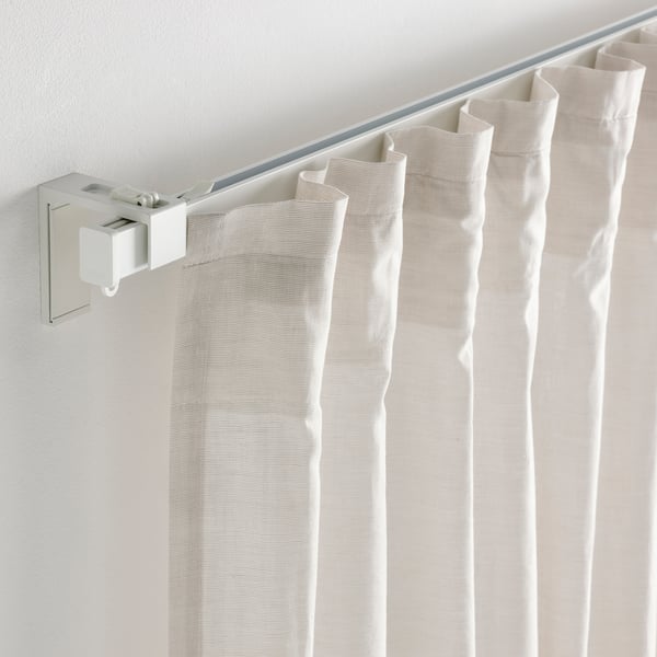 White curtains hang from adjustable metal rail on wall.