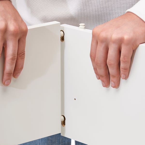 Person opening white VIHALS cabinet, gold hinges.