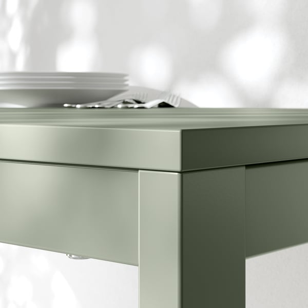 Close-up of modern, light green extendable tables corner, showcasing sleek design and sturdy build.