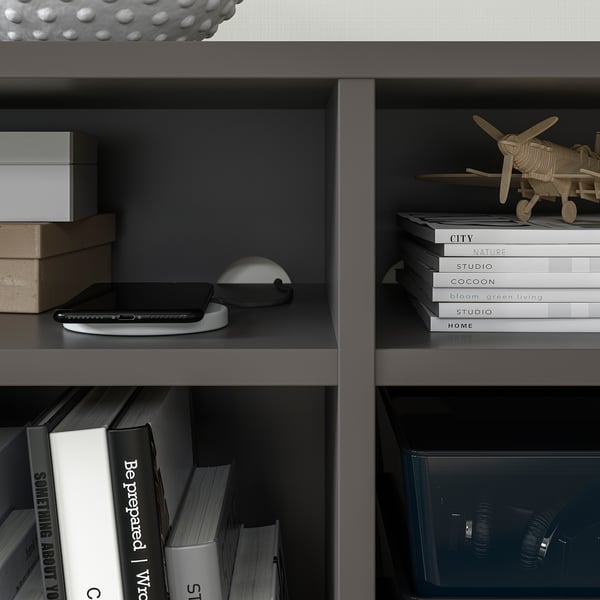 Modern black bookshelf with ipad, books, plane decor, and paper, wire box.