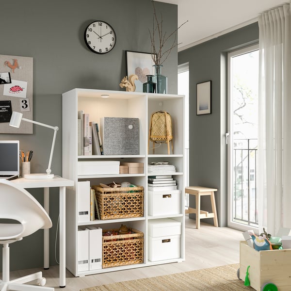 Modern home office with white storage, books, & clock.
