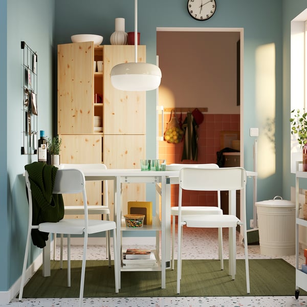 Bright, modern dining setup with white metal chairs and pine cabinet, minimalist design.
