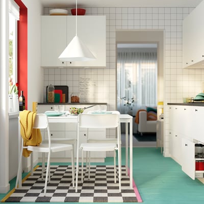 Bright kitchen with white VIHALS table and chairs, green floor, red window, and white tiles.
