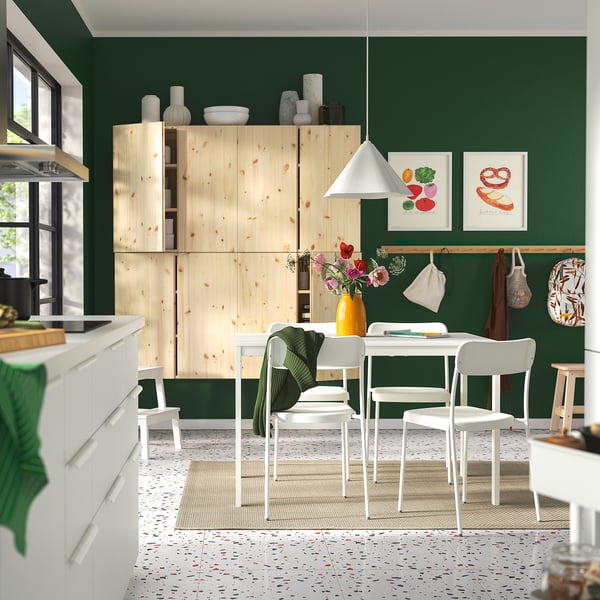 Modern kitchen with green walls, light wood cabinets, white dining set.
