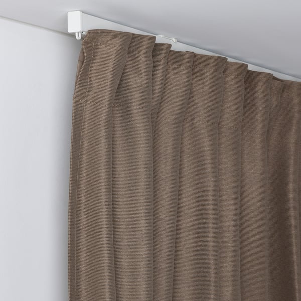 A curtain hung above a window, secured by a white rod and gliders, demonstrating its heat and light blocking abilities.