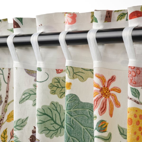 Floral curtains with hooks hang down, showing light filtering and privacy.