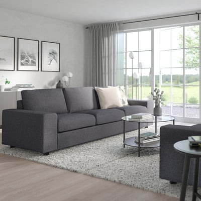 Modern grey VIMLE sofa set, large, with two sofas, chairs, glass coffee table, rug, lamps, plants, set against large windows with curtains.
